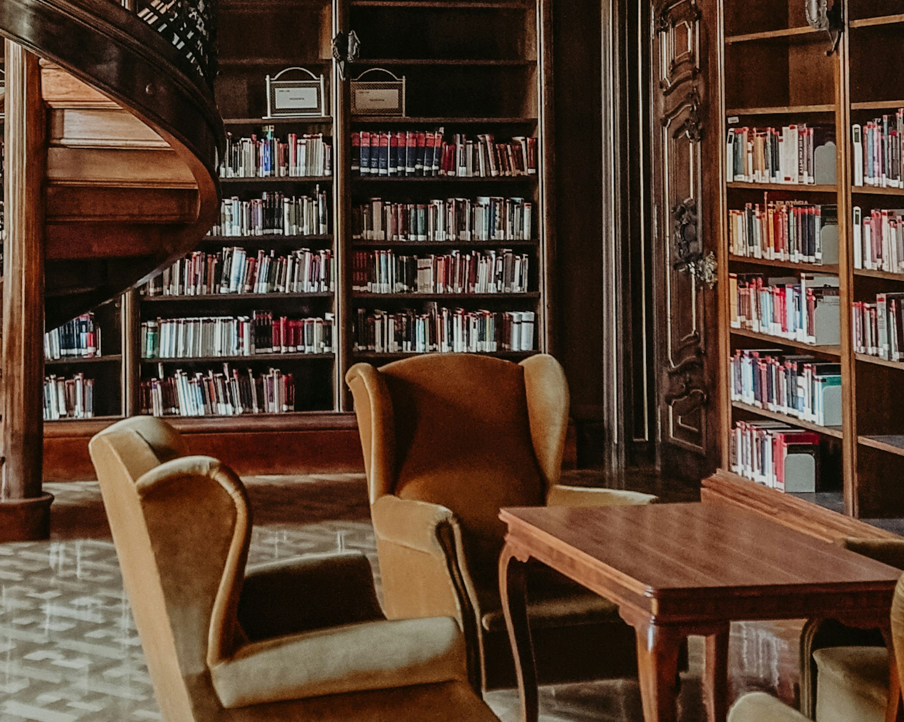 A corner of an ornate library with wingback armchairs